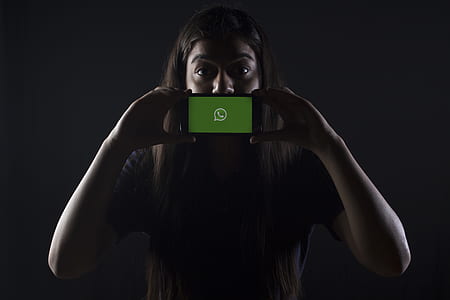 woman holding black smartphone covering her mouth thumbnail