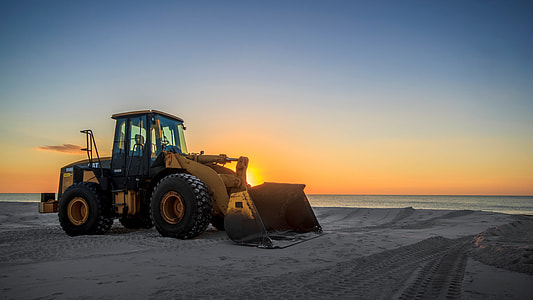 yellow and black bulldozer parked on grey sand thumbnail