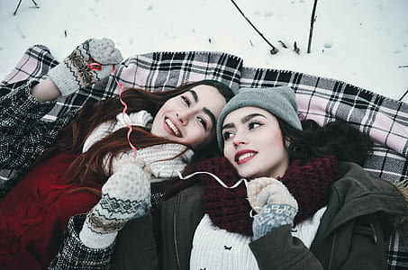 woman in gray knit cap beside woman in pair of white-and-black knit gloves thumbnail