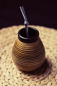 brown jar with black lid and grey straw on brown woven mat thumbnail
