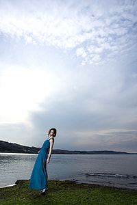 woman standing near body of water wearing blue dress thumbnail