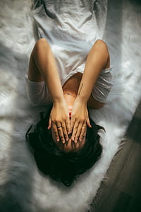 woman lying on bed covering her face thumbnail
