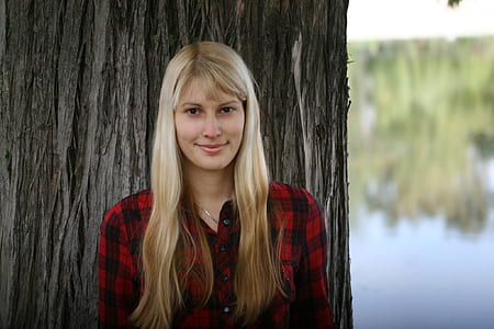 smiling woman leaning on tree during daytime thumbnail