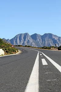 low-angle photo of concrete road curved towards gray mountain thumbnail