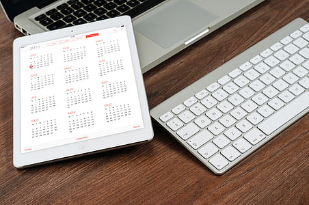 turned-on iPad displaying calendar beside Apple Wireless Keyboard and MacBook Pro thumbnail
