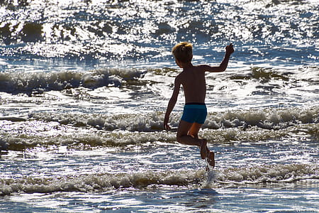 photo of boy walking on seashore thumbnail