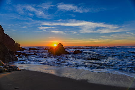 silhouette photo of rocks surrounded by body of water thumbnail