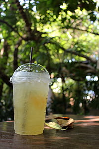Cup of iced lemon tea outside on a table in a tropical garden thumbnail