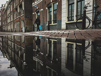 person in black suit walking reflection on body of water thumbnail