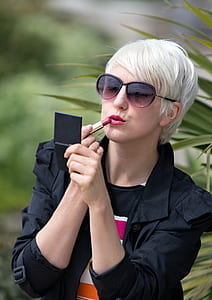 Blond Short Haired Woman Applying Pink Lipstick Outside thumbnail