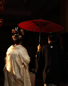 man in black traditional dress holding red umbrella thumbnail