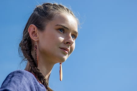 woman wearing blue top and pair of brown earrings thumbnail