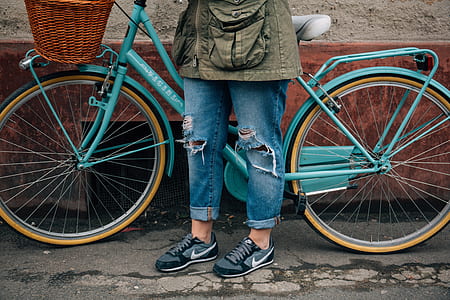 person wearing blue denim jeans standing near blue bicycle thumbnail