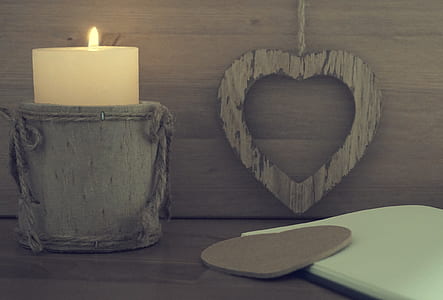 white pillar candle on gray container near brown wall thumbnail