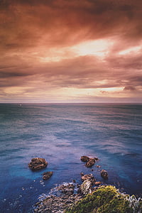 aerial view of rock formation on sea under gray sky during golden hour thumbnail