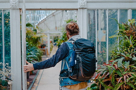 man wearing hiking backpack going inside a flower shed thumbnail