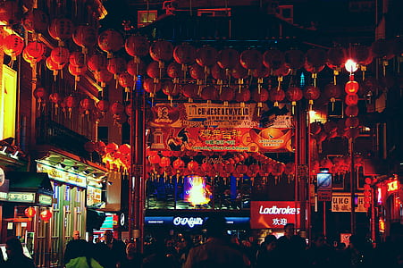 people walking on street with lots of red chinese lanterns hang at nighttime thumbnail