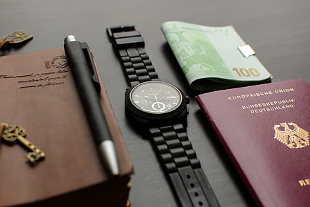 Round Black Chronograph Watch on Table Near Germany Passport an Banknote on Table thumbnail