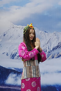 woman wearing pink and white floral dress standing near mountain background thumbnail
