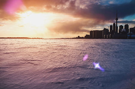 body of water beside city during sunset thumbnail