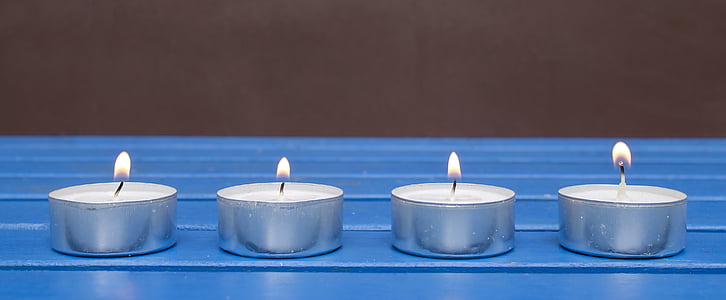 several lit round votive candles on blue surface thumbnail