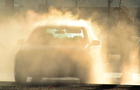 man holding pressure washer washing car thumbnail