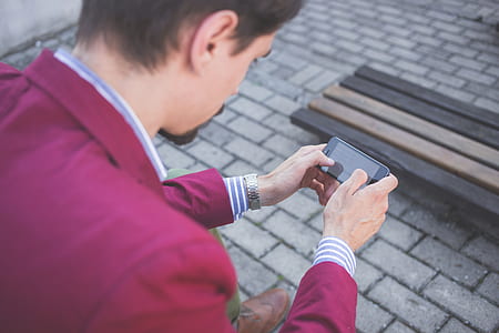 man sitting on bench while using smartphone thumbnail