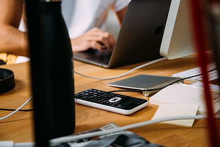 person using laptop computer near black calculator on brown table thumbnail