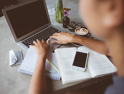 closeup photo of person holding laptop beside books and phone on table thumbnail