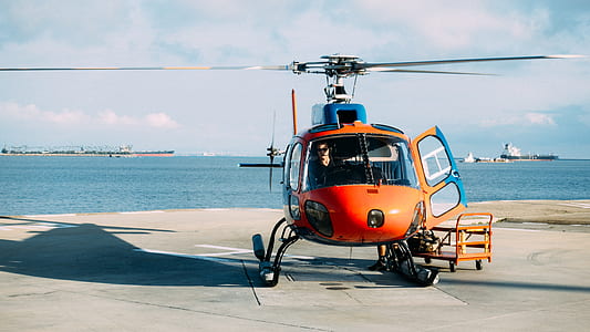 orange helicopter landed near ocean thumbnail