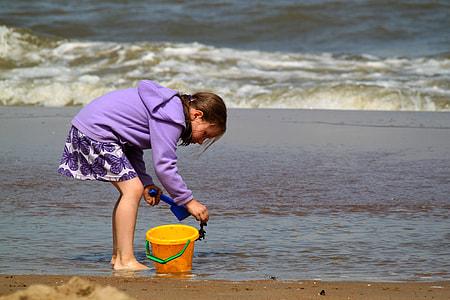 girl holding sand standing on the seashore thumbnail