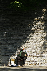 person playing accordion near wall thumbnail