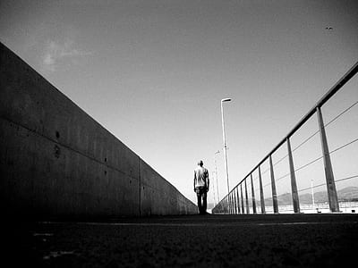 silhouette photography of man standing on sidewalk thumbnail