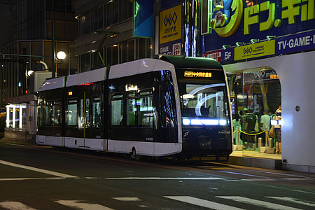 white bus on road near building at nighttime thumbnail