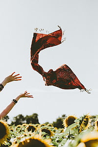 woman throwing red scarf above sunflower field thumbnail