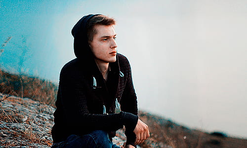 man wearing black hoodie seating on gray surface thumbnail
