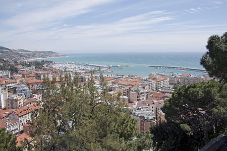 red-and-gray concrete village near body of water under white and blue sky thumbnail