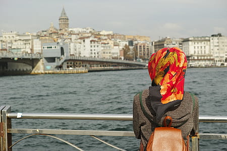 woman facing towards high-rise buildings near body of water thumbnail