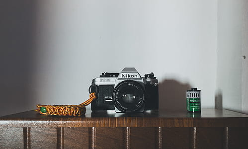 black and gray Nikon camera on brown wooden table thumbnail