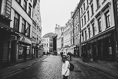 Grayscale Photo of a Woman Between Buildings Photo thumbnail