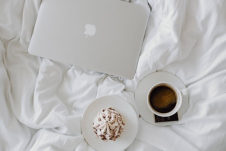 Woman working on a laptop while enjoying a breakfast coffee and chocolate in bed thumbnail