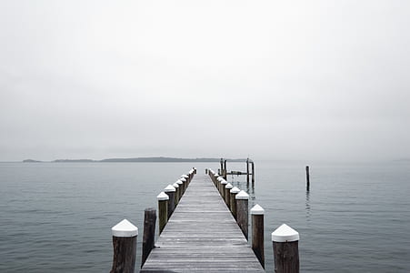 grey wooden dock between body of water during grey sky thumbnail