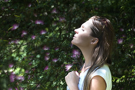 woman closing her eyes while standing beside pink flowers thumbnail