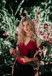 woman with red V_neck tank top holding red and white petaled flower bouquet during daytime thumbnail