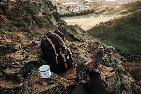 white mug on rock beside black and brown backpack thumbnail
