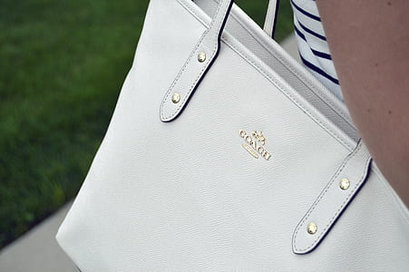 person wearing white Coach pebble leather tote bag thumbnail
