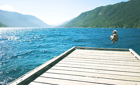 man jumping from dock through body of water thumbnail