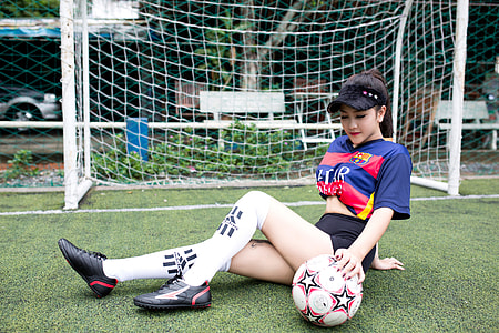 woman wearing blue and red jersey T-shirt sitting on green grass thumbnail