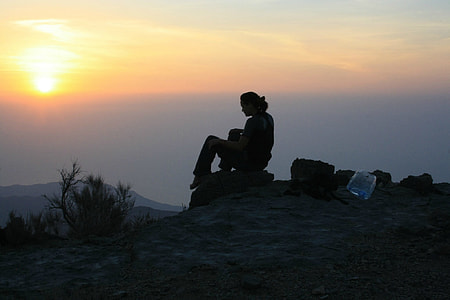 person sitting on stone watching the sunset thumbnail