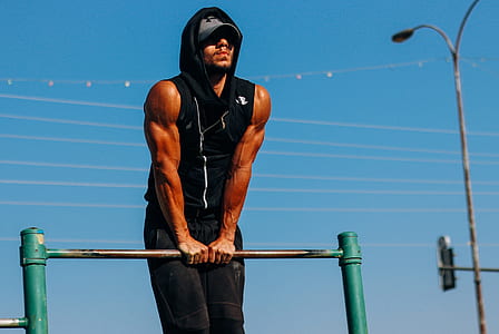muscled man in black vest holding bar fence thumbnail